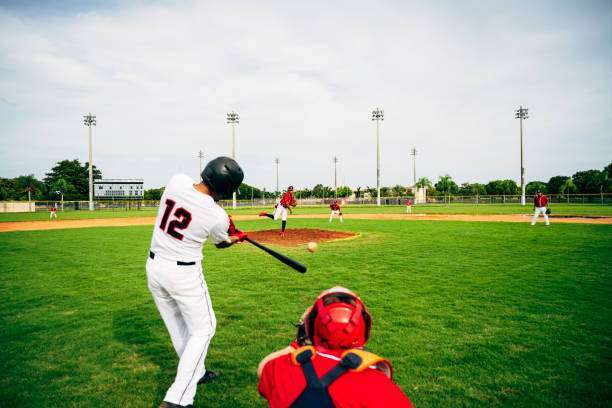 A playful man teaching a boy baseball exercises outdoors on a sunny day at a public park. baseball glove