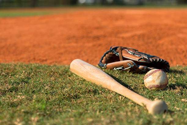 Baseball bat, glove, and ball on field grass.