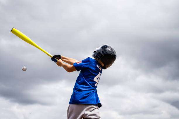 Young player hits a baseball; a good baseball glove is vital for fielding.