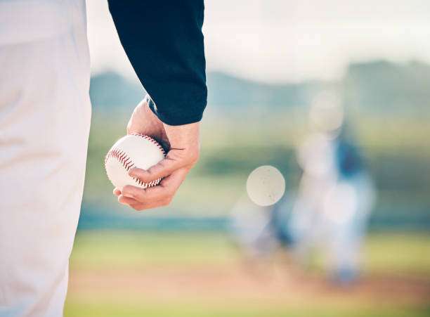 Baseball glove and ball on grass in brightly lit outdoor stadium.