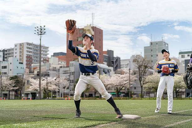 Japanese baseball player in uniform expertly catches a high ball with a baseball glove.