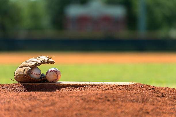 Baseball glove and ball on grass in brightly lit outdoor stadium.