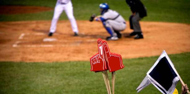 Fan memorabilia in foreground, with a catcher wearing a baseball glove at a game.