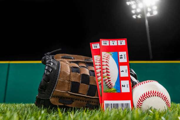 Baseball glove, tickets, and ball at night game.