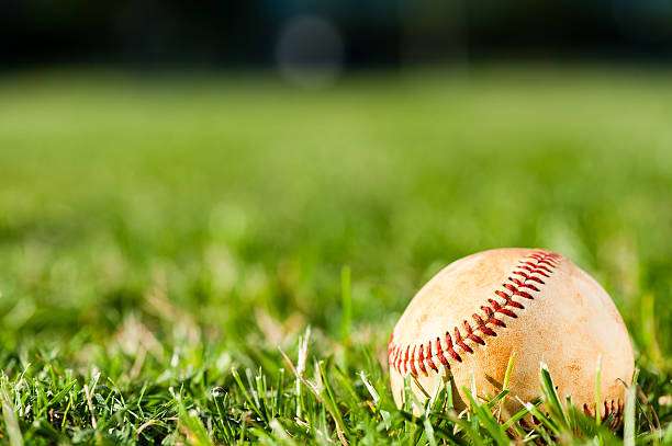 Person swinging a bat at a baseball on a sunny field, ready for their baseball glove.